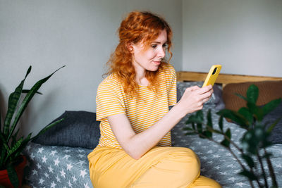 Young woman sitting on bed at home