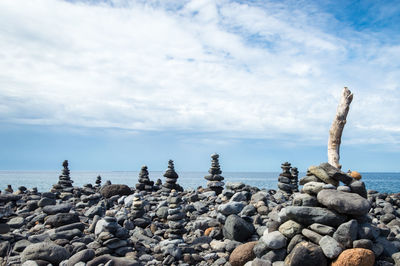 Stack of stones on shore against blue sky