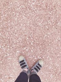 Low section of man standing on pink shoes