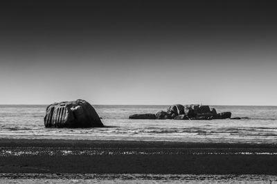 Rock formations in sea against clear sky