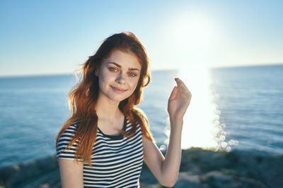 Portrait of smiling young woman against sea