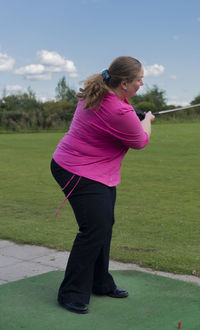 Side view of young woman standing on golf course