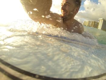 Man in water splashing against sky