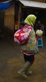 Woman walking on street holding bunch of flowers