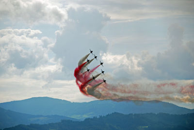 Helicopter flying over mountains against sky