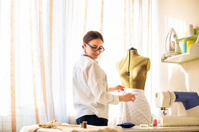 Young woman standing by table at home