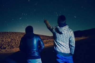 Rear view of two men in winter at night