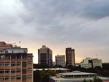Buildings in city against cloudy sky
