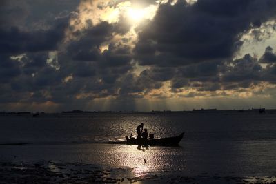 Silhouette man sailing on sea against sky during sunset