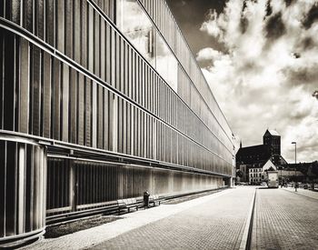 Footpath by modern buildings against sky in city