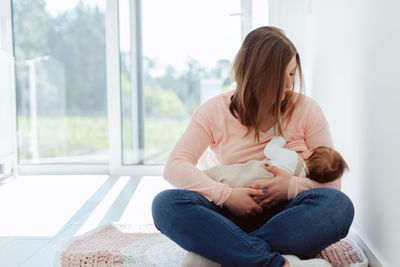 Mother breastfeeding daughter at home