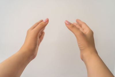 Midsection of woman holding hands against white background