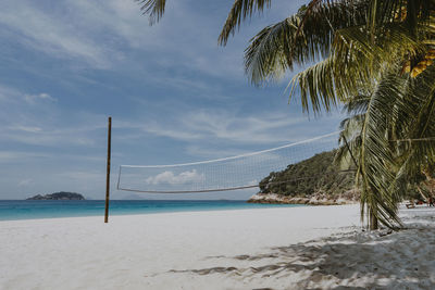 Volleyball net on tropical white sand beach with blue sky - nature and sport concept