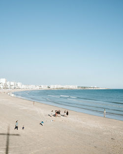 People on beach against clear sky