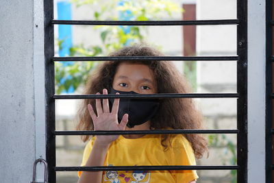 Portrait of young woman looking through window