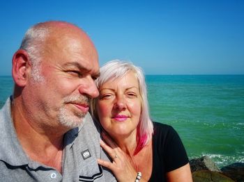 Close-up of smiling mature couple against sea at beach