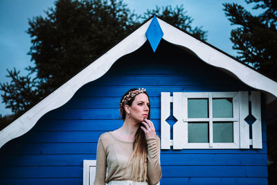 Portrait of young woman looking away against built structure