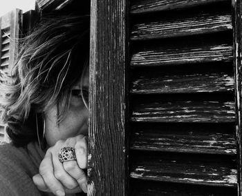 Portrait of woman hiding by wooden door