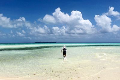 Rear view of man standing on beach against sky