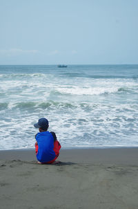 Rear view of boy sitting on beach