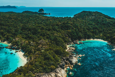 High angle view of rocks by sea against blue sky