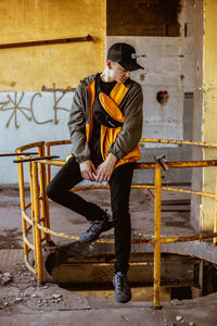 Full length of young man sitting against wall