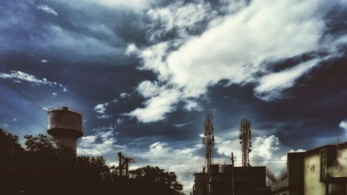 Low angle view of factory against cloudy sky