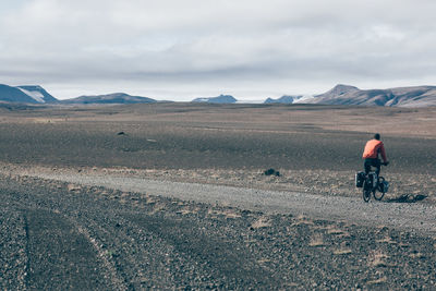 Rear vie of man riding cycle on dirt road