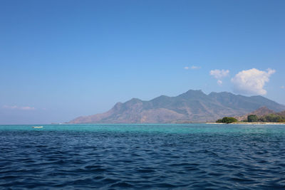 Scenic view of sea and mountains against blue sky