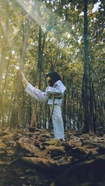 Woman standing by tree in forest