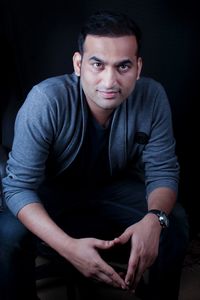 Portrait of young man sitting against black background