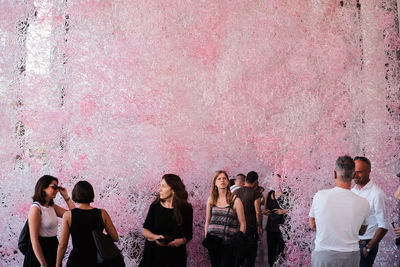 People standing against pink wall