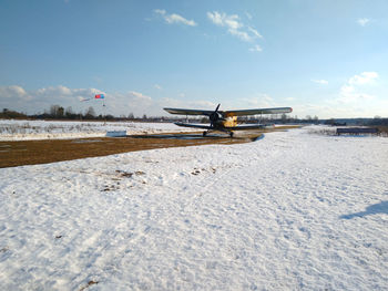 Airplane on snowy land against sky during winter