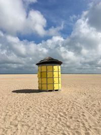 Yellow hut on beach against sky