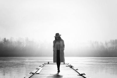 Confident woman walking alone along a jetty at the beach in winter