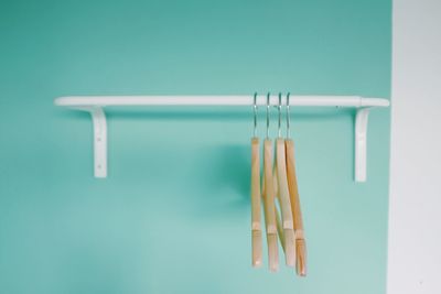 Close-up of clothespins hanging against blue background