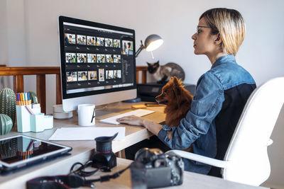 Female vlogger using computer during video conference in living room