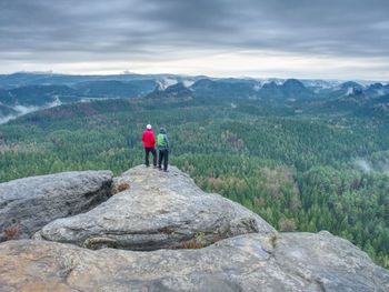 Friends in nature. tourists travelers with backpacks in the rocks watch the landscape in mist.