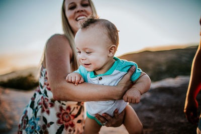 Mom swinging young infant in her arms and smiling