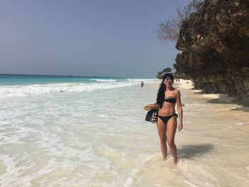 Full length of woman standing on beach against clear sky