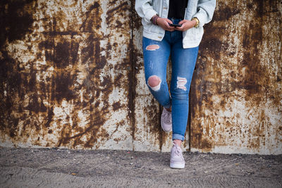 Low section of woman standing against wall