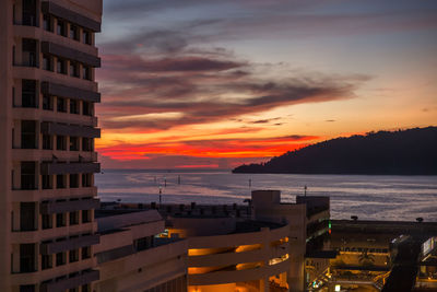 High angle view of buildings by sea against sky during sunset