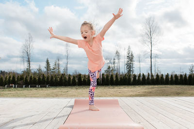 Young girl balancing on a yoga mat in her back yard at home