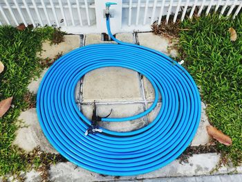 High angle view of water pipes rolled up on footpath in yard