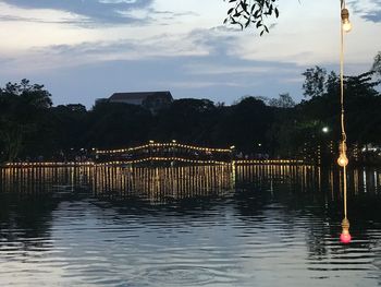 Illuminated bridge over river against sky at sunset