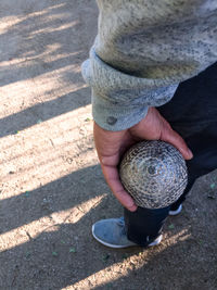 Low section of man holding boccia ball while standing on footpath