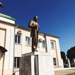 Low angle view of statue against building against clear blue sky