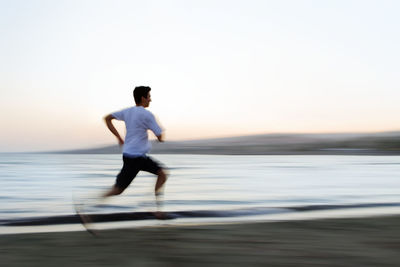 Blurred motion of man running against sea during sunset