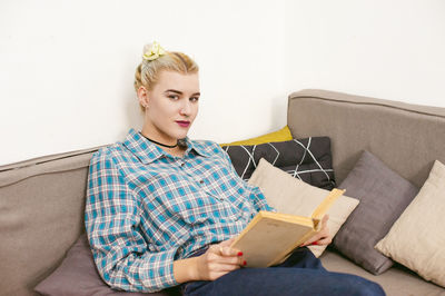 Young woman sitting on sofa at home