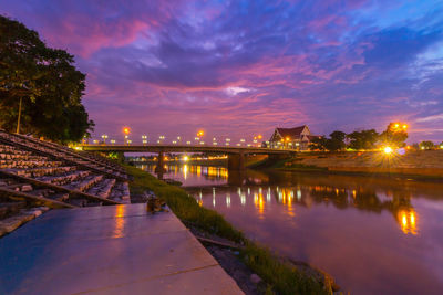 Illuminated bridge over river against sky at night